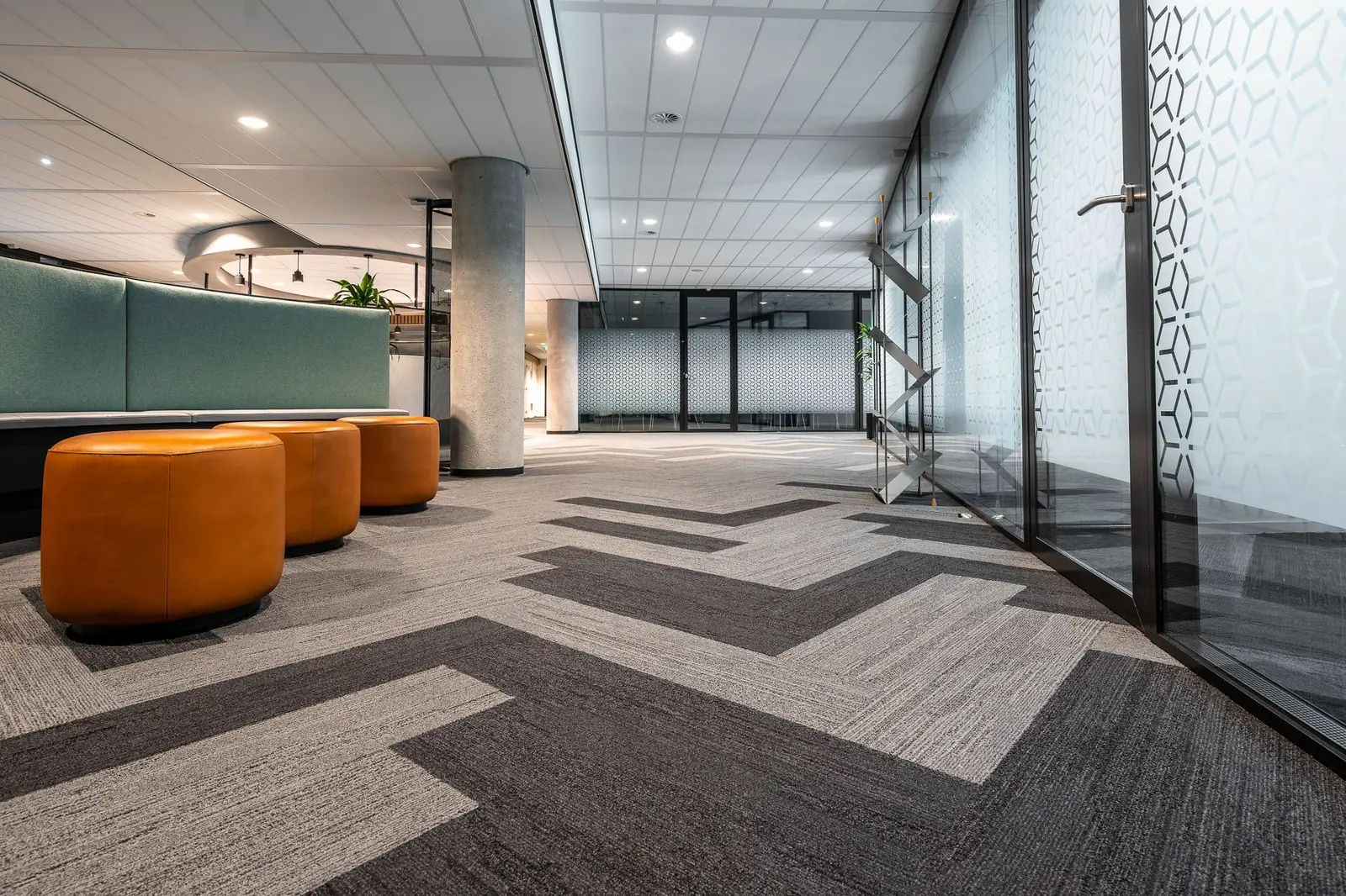 A modern office corridor with patterned carpet and glass doors