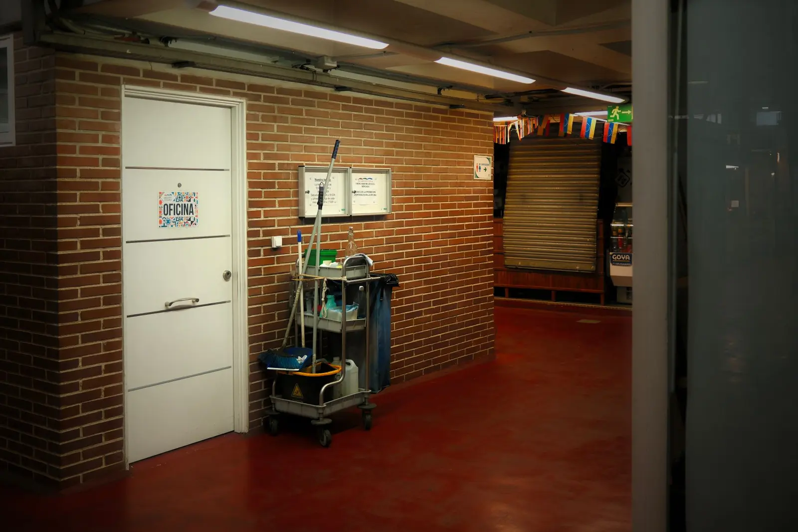 A cleaning cart stocked with supplies in a lit corridor outside an office door