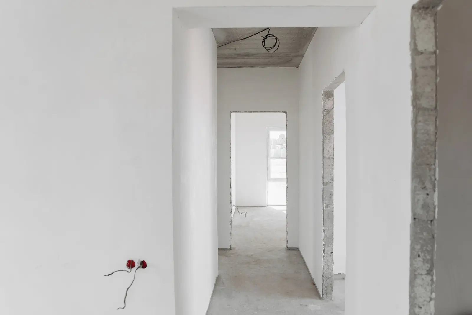 An unfinished building interior with white walls and empty door frames